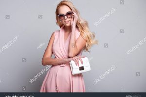 stock-photo-beautiful-fashionable-young-blonde-woman-wearing-sunglasses-pink-dress-purse-in-a-studio-spring-1967266771