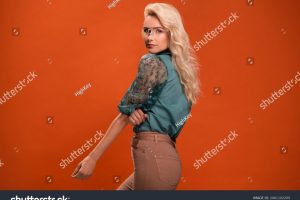 stock-photo-beautiful-fashionable-young-woman-in-a-studio-over-orange-background-wearing-green-blouse-beige-2061102209