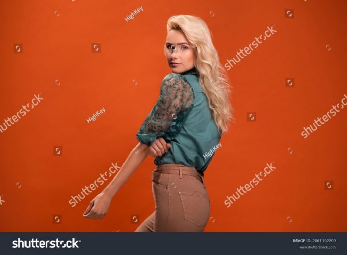 stock-photo-beautiful-fashionable-young-woman-in-a-studio-over-orange-background-wearing-green-blouse-beige-2061102209