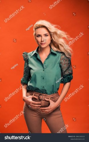 stock-photo-beautiful-fashionable-young-woman-in-a-studio-over-orange-background-wearing-green-blouse-beige-2061102212