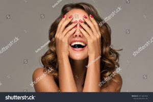 stock-photo-beautiful-woman-with-curly-hair-and-red-nails-manicure-girl-happy-laughs-closes-her-face-with-a-1911831463