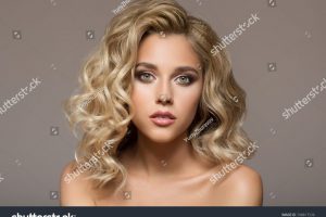stock-photo-blonde-woman-with-curly-beautiful-hair-smiling-on-gray-background-748817536