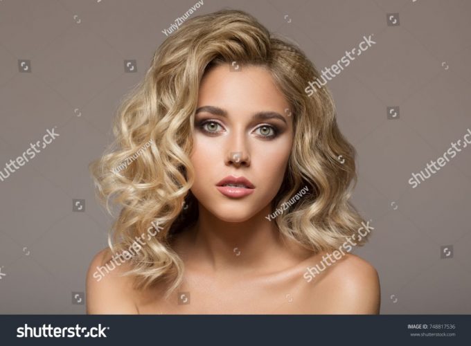 stock-photo-blonde-woman-with-curly-beautiful-hair-smiling-on-gray-background-748817536