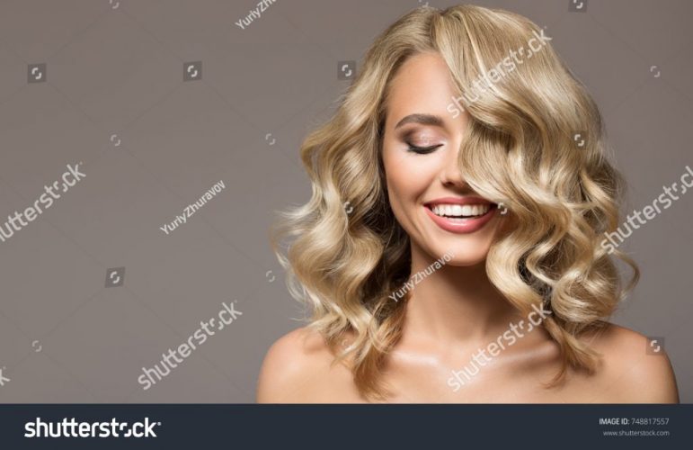 stock-photo-blonde-woman-with-curly-beautiful-hair-smiling-on-gray-background-748817557