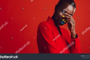 stock-photo-glamorous-female-model-on-red-background-african-woman-with-buzz-cut-hairstyle-and-vibrant-makeup-1725716320