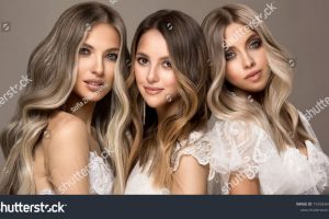 stock-photo-three-beautiful-girls-in-white-wedding-dresses-with-hair-coloring-in-ultra-blond-stylish-1935834508